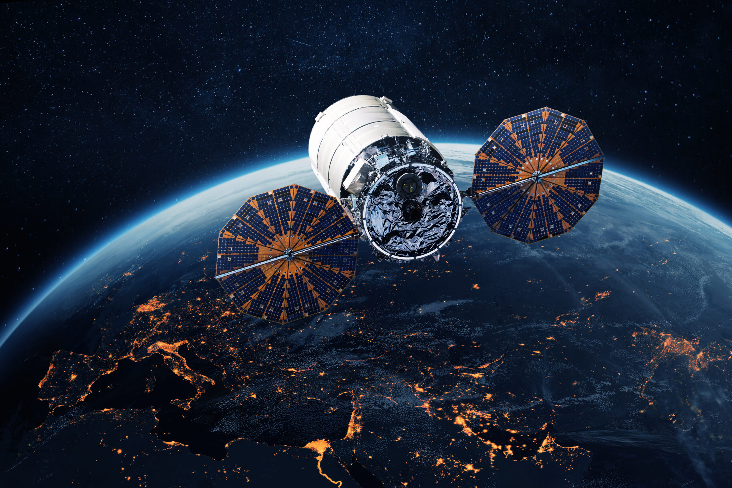 Satellite with extended solar panels orbiting above Earth at night, illustrating space infrastructure and satellite technology.
